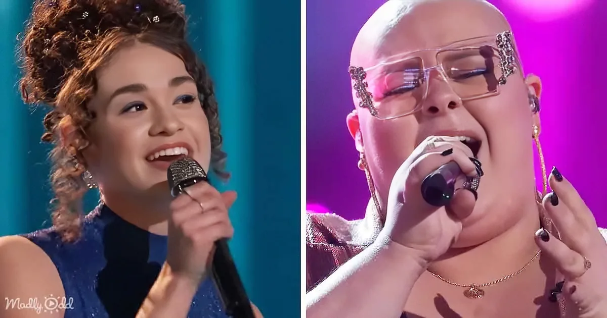 A woman with curly hair sings into a microphone, while another woman with glasses and a shaved head also sings into a...