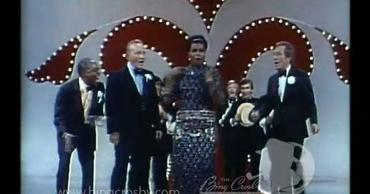 Three men in tuxedos, one with a bow tie, smiling and posing together.