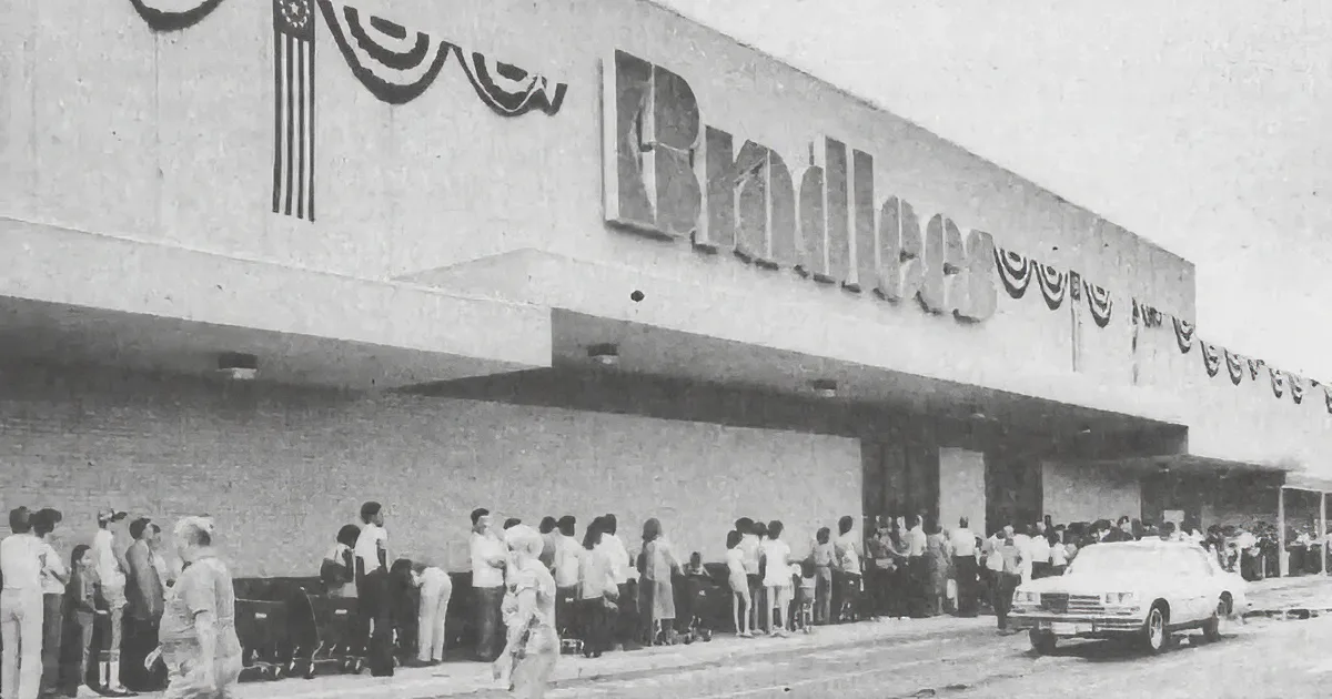 A black-and-white image of a Bradlee's store with a large sign, brick facade, and empty parking lot.