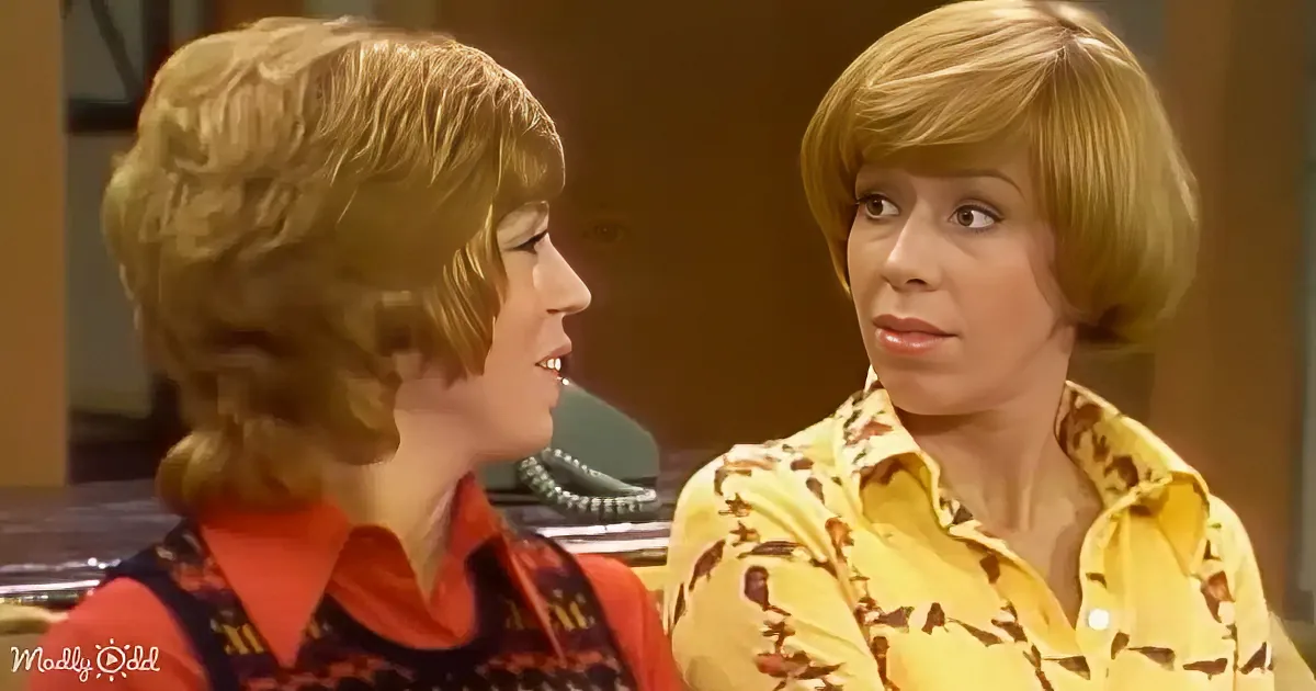 Two women with short blonde hair, one in a red and black patterned top, the other in a yellow floral shirt, appear to be...