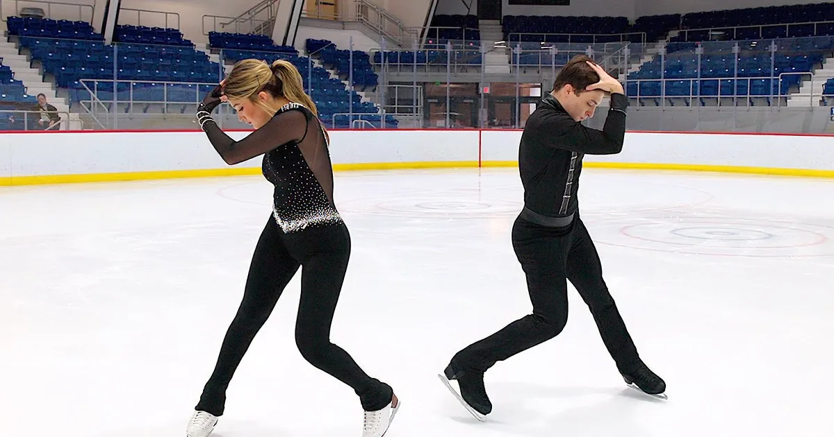 A figure skating couple glides gracefully on ice, performing a synchronized move.