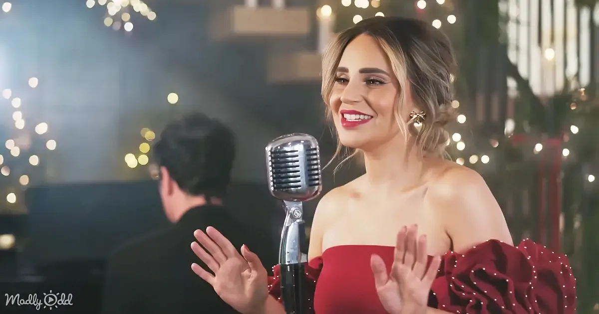A woman in a red dress sings into a vintage microphone, smiling with her hands raised.