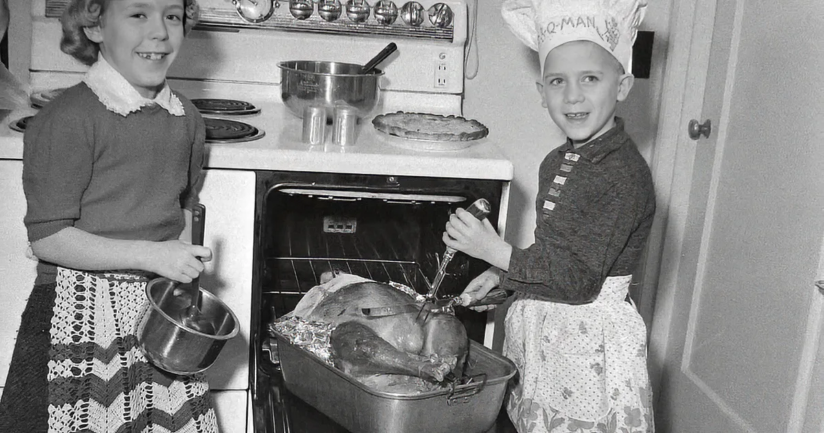 Woman in pink dress holds roasted turkey over dining table with family, vintage setting.