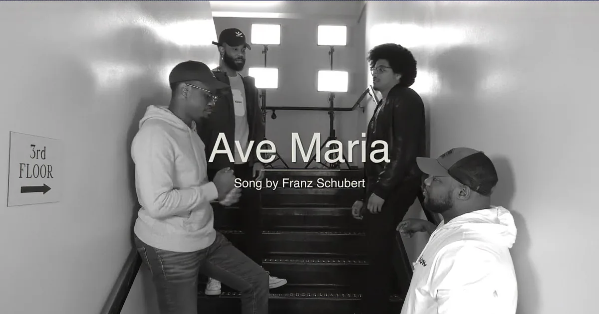 Four individuals are gathered around a staircase, engaged in conversation, with a sign indicating the 3rd floor in the...