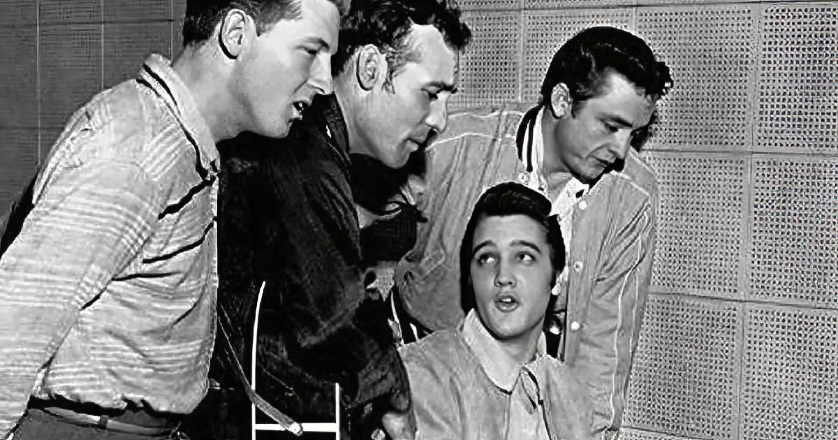 Elvis Presley smiles while playing piano, surrounded by a crowd in a lively setting.