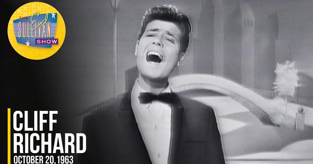 A smiling man with a classic hairstyle, wearing a suit, in a black-and-white image.