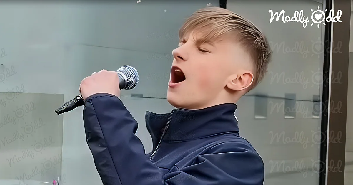 A young person in a dark jacket sings passionately into a microphone, with "Madly Odd" watermark visible.