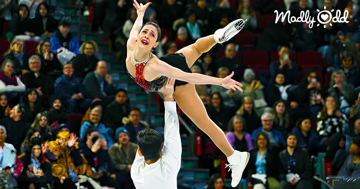 A figure skater in a dramatic pose is lifted by a partner in front of an audience.