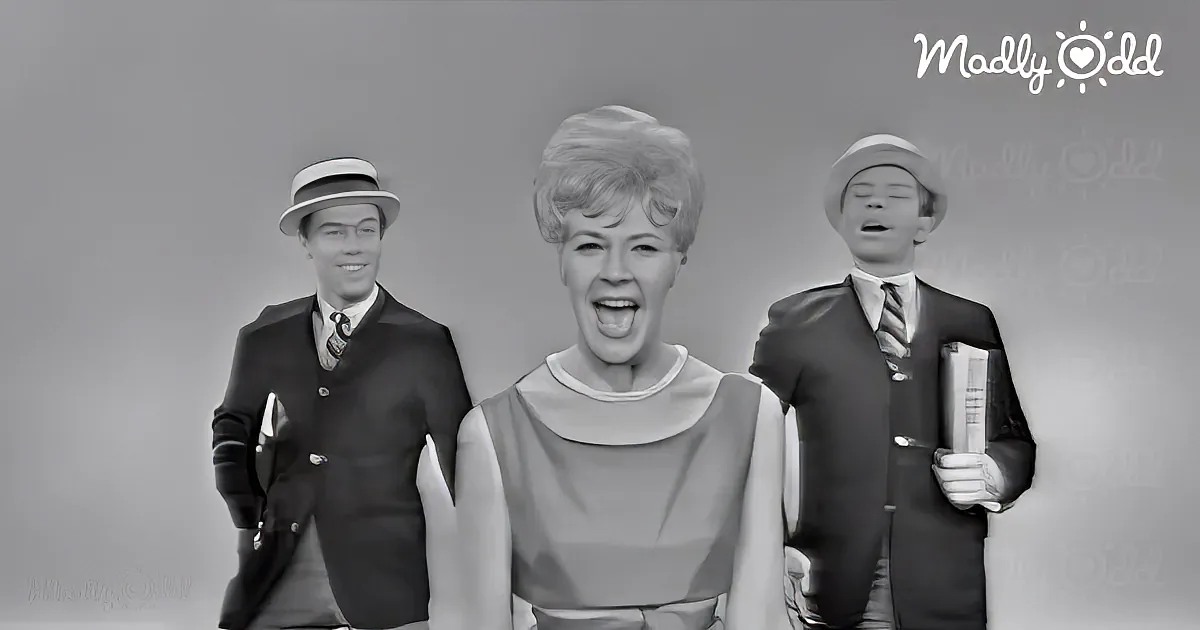 A woman in a dress with two men in suits and hats behind her, all in black and white.