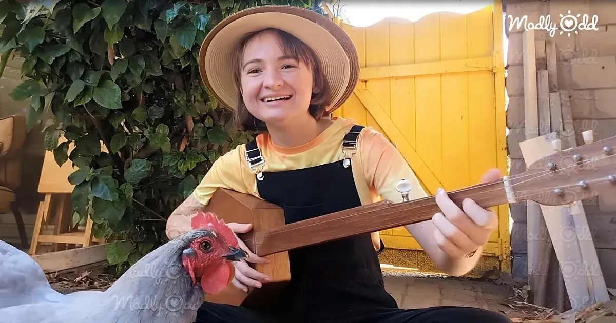 A person in a straw hat and overalls holds a guitar while a chicken pecks at it.