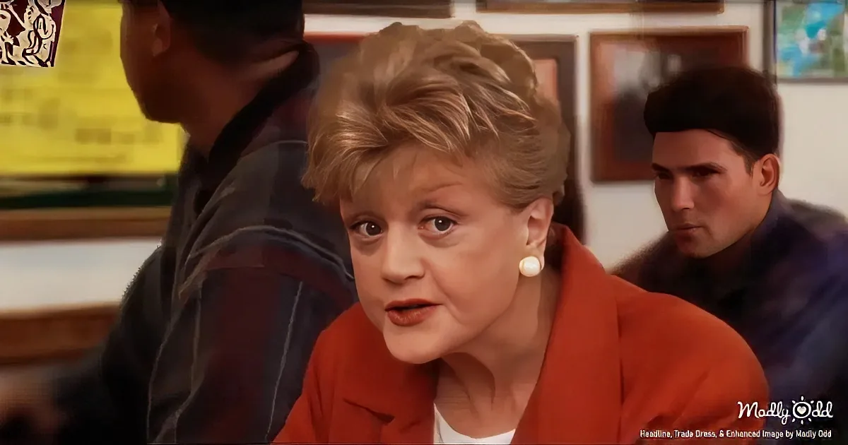 A woman in an orange blazer and pearl earrings looks concerned in a classroom setting.