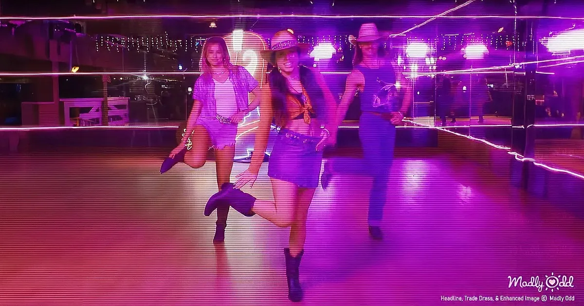 Three women in cowboy hats and boots dance on a vibrant purple-lit dance floor.