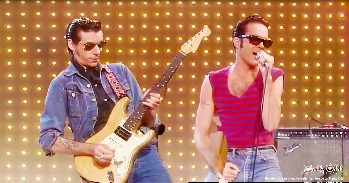 Two musicians perform on stage, one playing guitar and the other singing into a microphone.