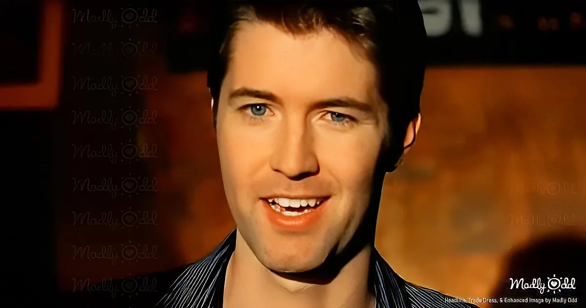 A smiling man with blue eyes and short brown hair, wearing a striped shirt, is the main subject.