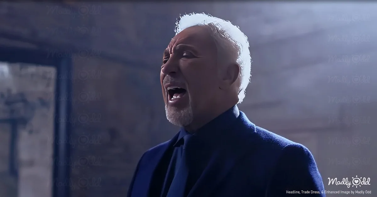 An older man with white hair and beard, wearing a blue suit, sings passionately with his eyes closed.