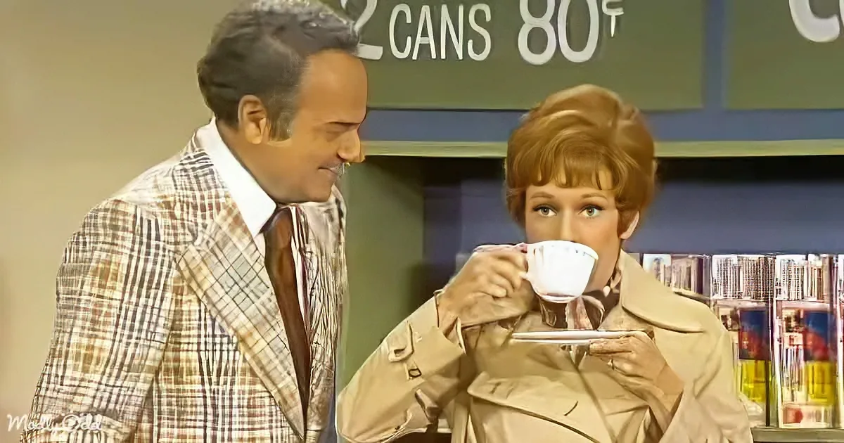 A man in a plaid suit and a woman in a beige coat are interacting in a store setting.