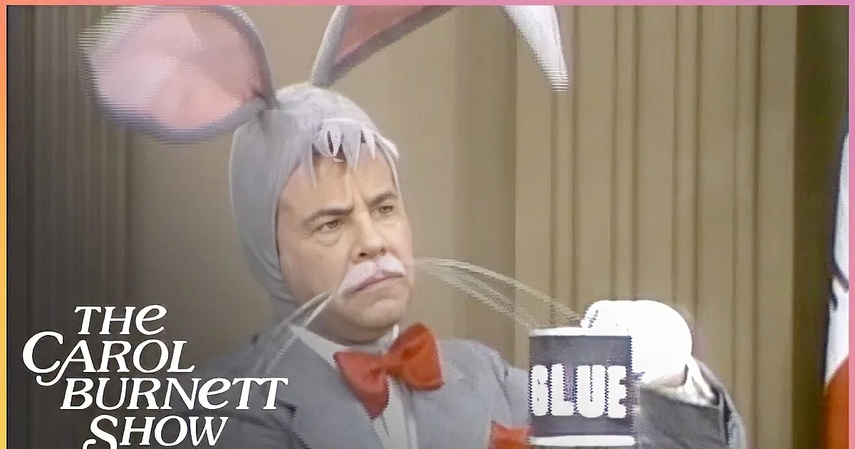 A man in a suit with bunny ears and a mustache, wearing a red bow tie.