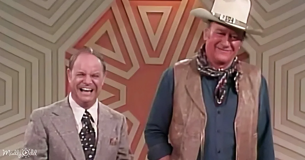 A man in a cowboy hat and vest stands next to another man in a suit, both smiling.