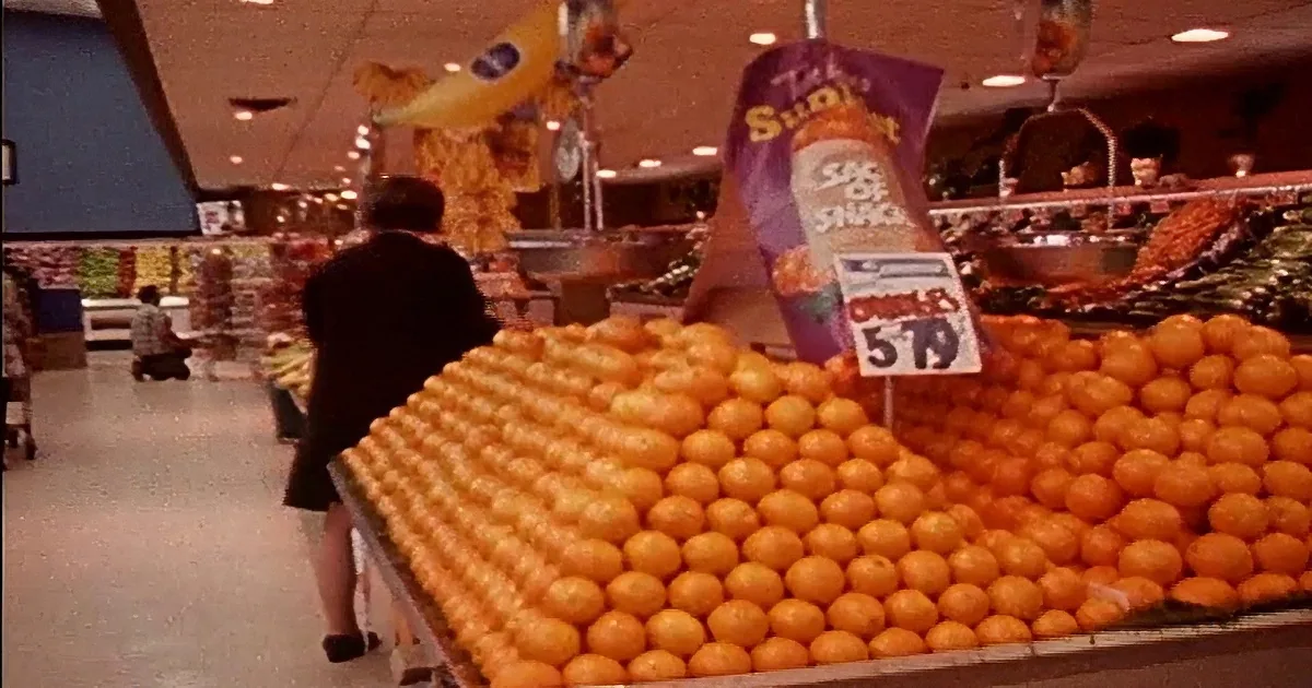 A hand presses buttons on an old cash register, displaying "00.69" and a grocery receipt.