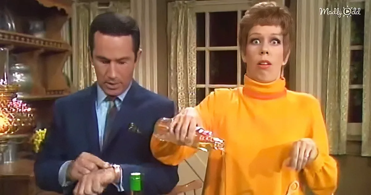 Woman in orange dress pours liquid while man in suit watches, both in a vintage setting.