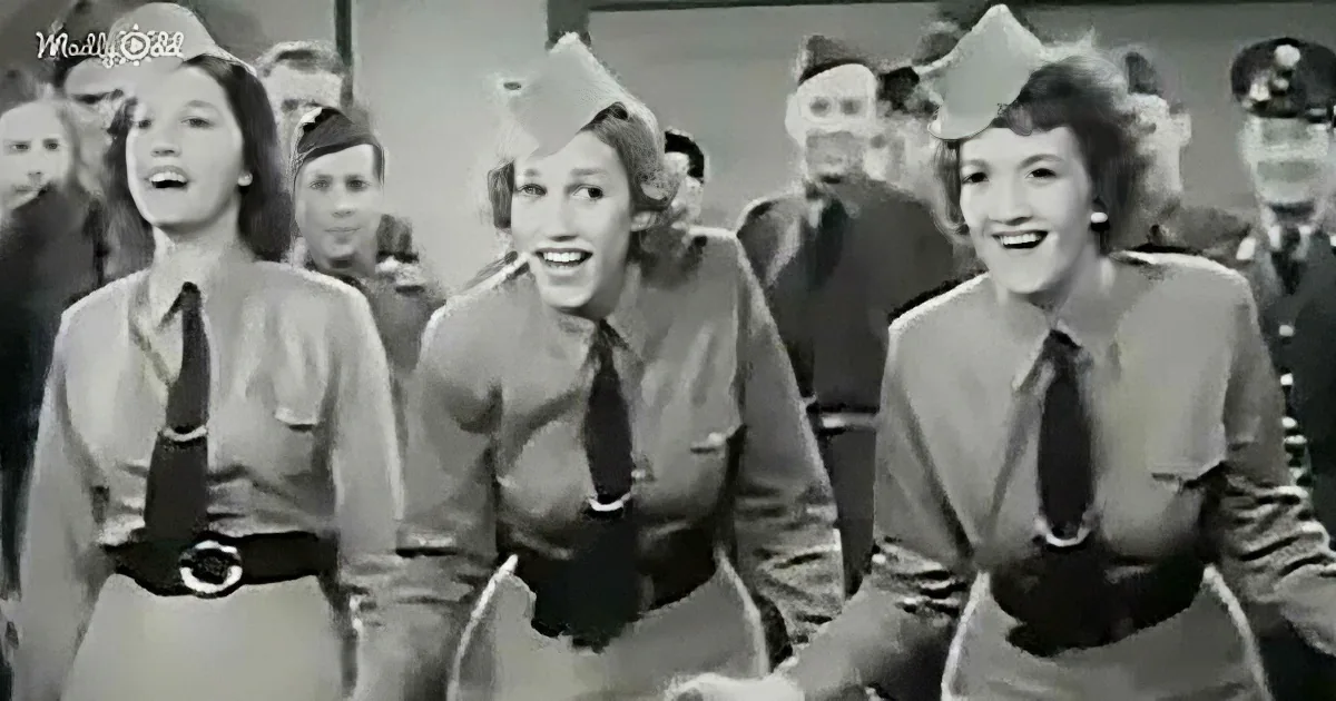 Three women in uniform with ties and belts, smiling and standing together in a group.