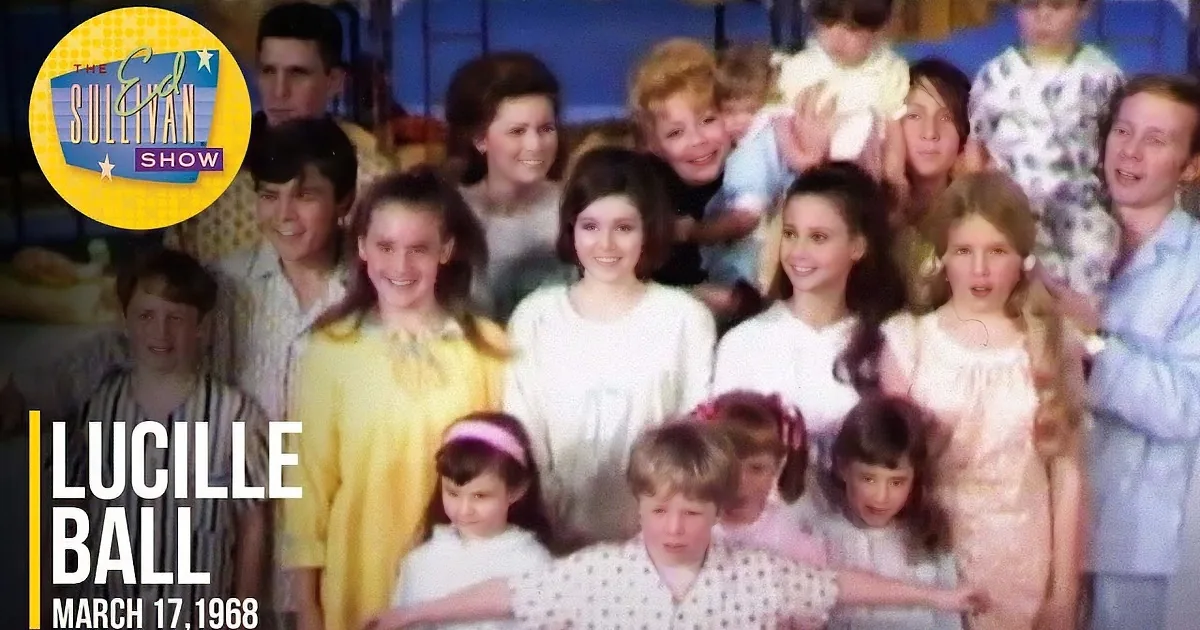 A group of children and adults in pajamas smile for a photo in a tent-like setting.