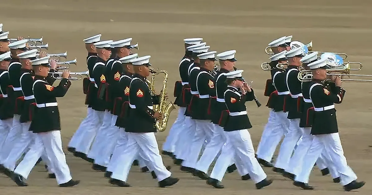 A marching band in uniform plays instruments while marching in formation.
