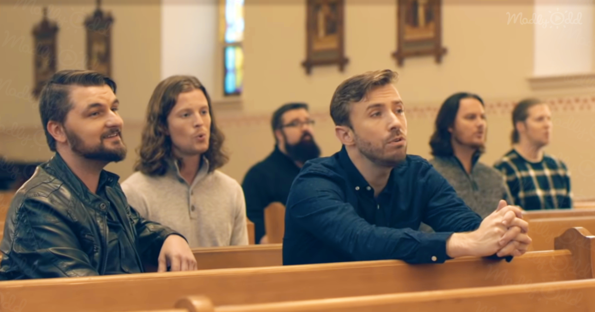 A man in a blue shirt sits in a church pew with others, hands clasped, looking forward.