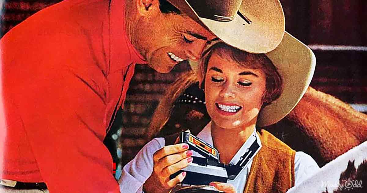 A man in a red shirt and cowboy hat leans over a woman in a brown vest, both smiling, as she holds a small object.